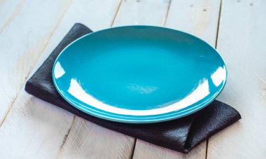 Beyaz ahşap bir masada boş mavi tabak.