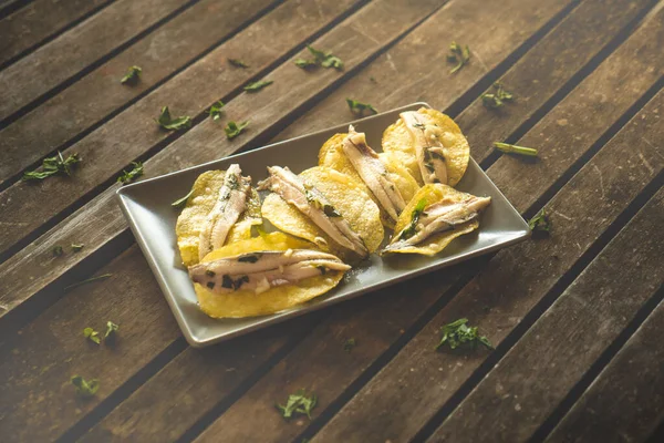 土豆片与腌制的大头菜在黑暗的矩形板上的深褐色木制桌子 在酒吧里吃的典型的西班牙食品 — 图库照片