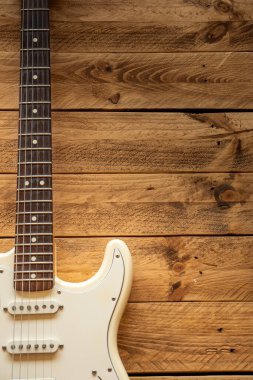 Kahverengi ahşap bir masada, kopyalama alanı olan beyaz elektro gitar..