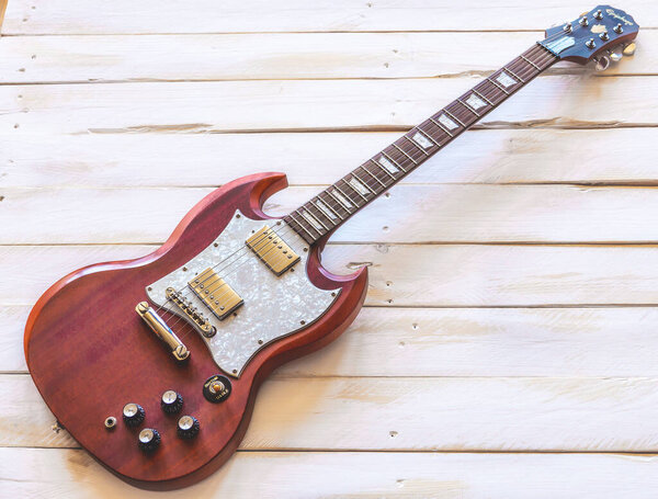 Classic red and white electric guitar on a white wooden table, with copy space.