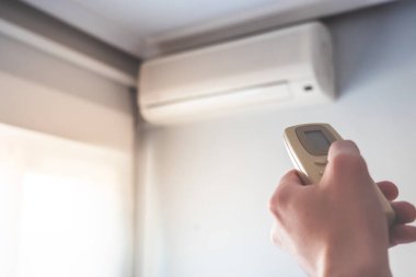 Klimalı uzaktan kumanda ev sıcaklığını değiştiriyor. Seçici odaklı fotoğraf. 