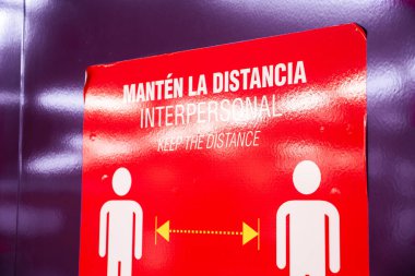 Coronavirus enfeksiyonlarını önlemek için Madrid metrosu (Metro de Madrid) koridorlarındaki sosyal mesafeyi korumak için Mantn la Distancia 'nın kişiselleştirdiği metni içeren bir etiket. Mesafeyi koru.