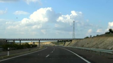 Güneşli bir günde, kirli camlı bir arabanın içinden, çayırların ve dağların olduğu bir İspanyol yolunun ve ufkun önü..