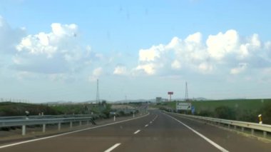 Güneşli bir günde, kirli camlı bir arabanın içinden, çayırların ve dağların olduğu bir İspanyol yolunun ve ufkun önü..