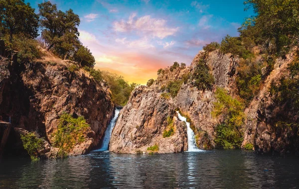 Madrid 'de Cascada del Hervidero adı verilen doğal şelale, gün batımında turuncu ve mavi bir gökyüzü ile. 