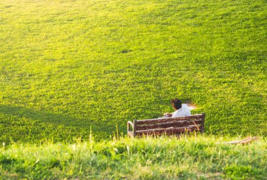 Güneşli bir günde yeşil çimlerle bir bankta oturan adam rahatlıyor.. 