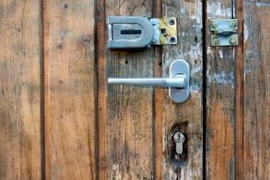 Güvenlik cihazları olan kahverengi ahşap bir kapının küçük bir bölümü, kilit ve cıvata. Kötü yaşlanmış. Nuertingen, Almanya