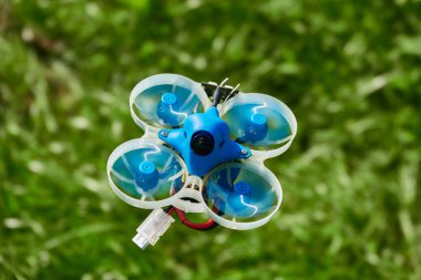 Küçük mavi İHA da yarışta, beyazlı koruyucu gondol ve bulanık yeşil arka plan. Almanya.