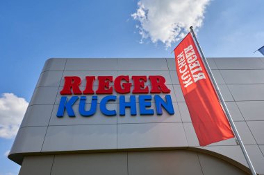 Goeppingen, Almanya - 21 Mayıs 2020: Mutfak Rieger cephesi, mavi ve kırmızı harfler, renkli bayrak, bulutlu mavi gökyüzü ile bol gün ışığı. Goeppingen.