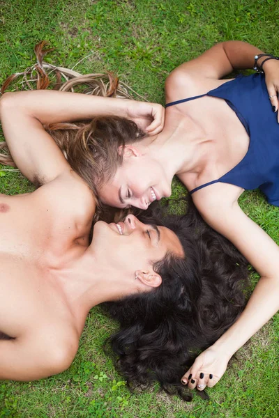 Bella giovane coppia con i capelli lunghi sono sdraiati sull'erba. Vista dal punto più alto . — Foto Stock