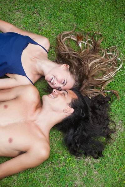 Beautiful young couple with long hair are lying on the grass. View from the top point. — 图库照片