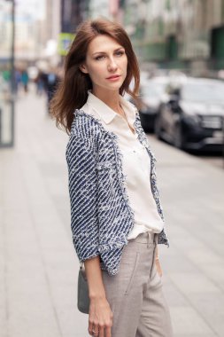 Zarif giysiler içinde güzel genç iş kadını açık havada duruyor ve mesafe içine bakar