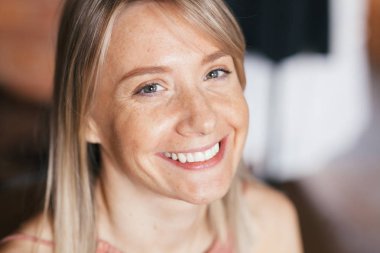 Çiller ile güzel gülümseyen mutlu sarışın genç kadının yakın çekim doğal sıcak ışık portre. Kadın içeride. Yaşam tarzı, güneş lekeleri