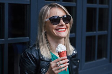 güneş gözlüğü güzel gülümseyen genç kadın sarışın elinde dondurma ile kırmızı boynuz tutar