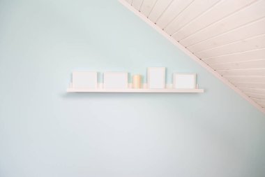 Beyaz çerçeveli beyaz bir raf ve tavan arasında bej bir mum. Açık mavi duvar. yüksek tuş