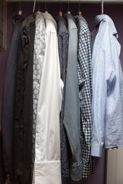 Farklı renkte ve sakin erkek gömlekleri gardıroptaki barda asılı.