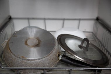 Bulaşık kurutma makinesinin metal rafında cam kapaklı gri çelik tava