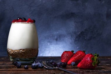 Mısır gevreği çilekli yoğurt ve ahşap tabanlı yabanmersini.