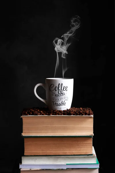 cup of coffee with smoke on a book and coffee beans