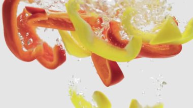 Kırmızı ve Sarı Paprika Dilimleri Suya Düşüyor, Beyaz Arkaplanda İzole Edilmiş
