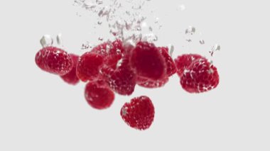 Suya düşen taze ahududular, beyaz arka planda izole edilmiş.