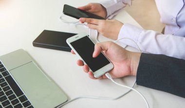 Cep telefonunu enerji bankasına bağlayan iki kişi. Teknoloji aygıtı paylaşım konsepti.