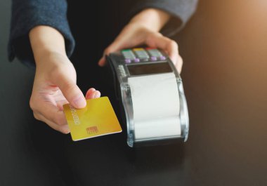 Dükkanda ürün satmak için kredi kartı okutma makinesi kullanan bir kadın. Kredi kartıyla harcama kavramı.