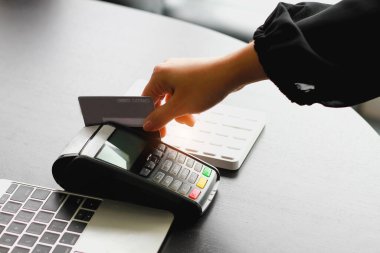 Dükkanda ürün satmak için kredi kartı okutma makinesi kullanan bir kadın. Kredi kartıyla harcama kavramı.