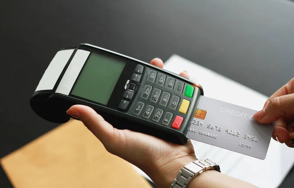 Dükkanda ürün satmak için kredi kartı okutma makinesi kullanan bir kadın. Kredi kartıyla harcama kavramı.