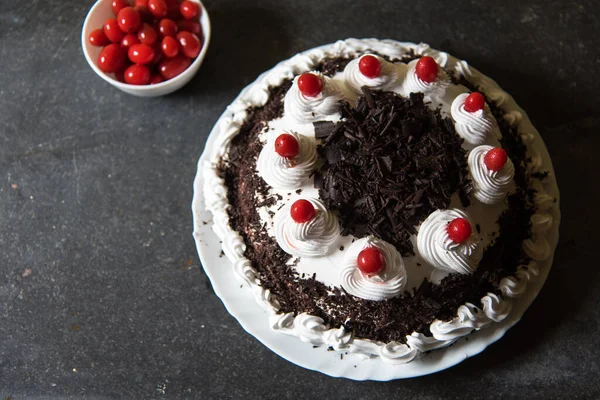 Cherries and Black forest cake with use of selective focus on a portion of the cake with rest of the cake and cherries blurred.