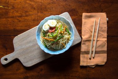 Arka planda yemek çubukları olan bir kasede seçici odaklı erişte.
