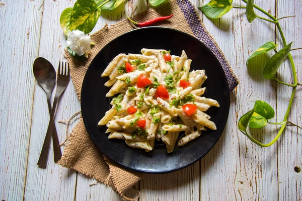 Top view of cheese pasta with vegetables on a plate and condiments with use of selective focus