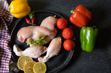 Siyah arka planda, tavada sebzeli çiğ tavuğu kapat. 