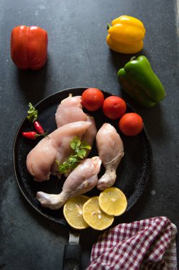 Taze tavuk filetosu ve çiğ sebzeler siyah bir tavada seçici odaklanma ile birlikte..