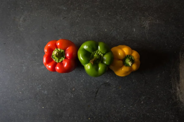 Top view of red, yellow and green bell peppers or capsicums on a background