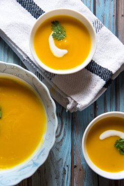 Beyaz kâse içinde balkabağı çorbası iki küçük kâseye servis edilir..