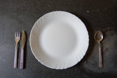 Siyah arka planda çatal ve bıçaklı boş bir tabak..