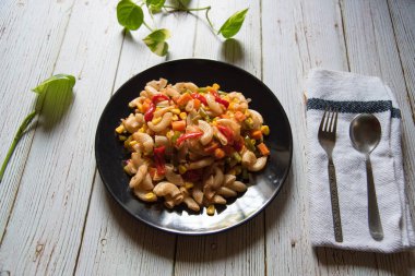 Siyah tabakta et ve sebzeli bir tabak makarna