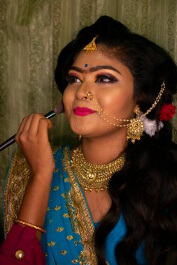 Hintli bir kız güzellik salonunda resepsiyon partisi makyajı yapıyor.