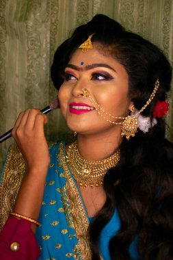 Hintli bir kız güzellik salonunda resepsiyon partisi makyajı yapıyor.