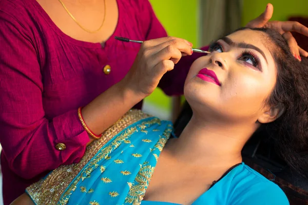an indian teenage girl taking face makeup at a beauty salon