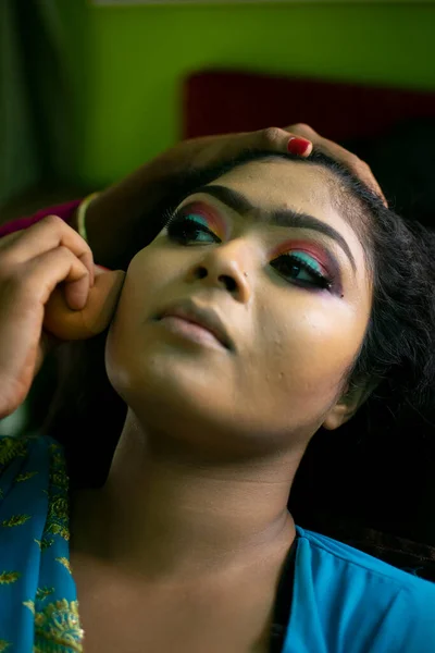an indian teenage girl taking face makeup at a beauty salon