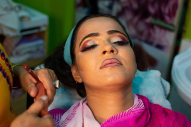 Güzellik salonunda göz makyajı yaptıran Hintli bir kadın.