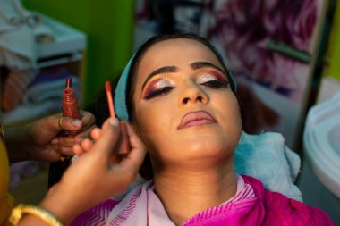 Güzellik salonunda göz makyajı yaptıran Hintli bir kadın.