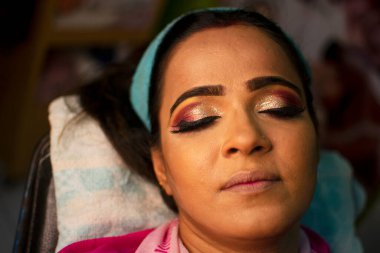 Güzellik salonunda göz makyajı yaptıran Hintli bir kadın.