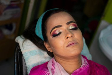 Güzellik salonunda göz makyajı yaptıran Hintli bir kadın.