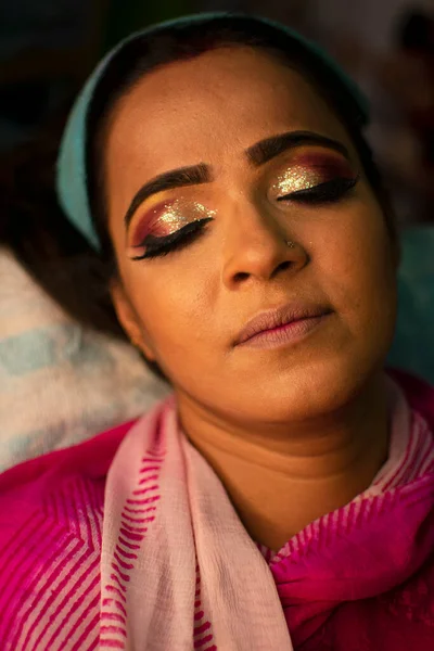 Güzellik salonunda göz makyajı yaptıran Hintli bir kadın.