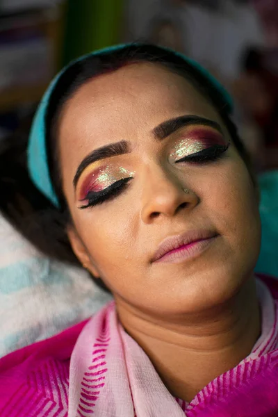 an indian woman getting eye makeup at beauty parlour