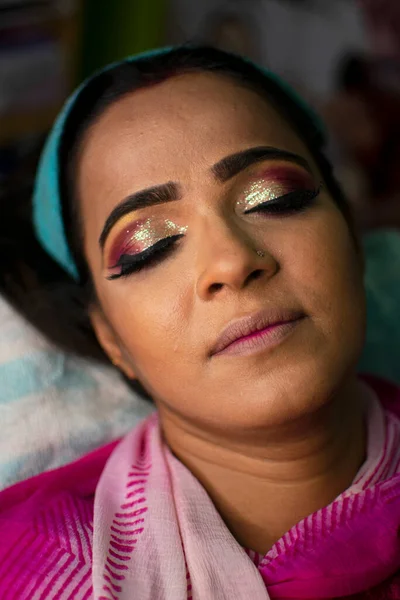 Güzellik salonunda göz makyajı yaptıran Hintli bir kadın.