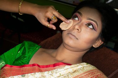 Hintli bir kadın gelin makyajı yaptırıyor.